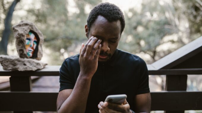スマホを見ながら悩んでいる男性